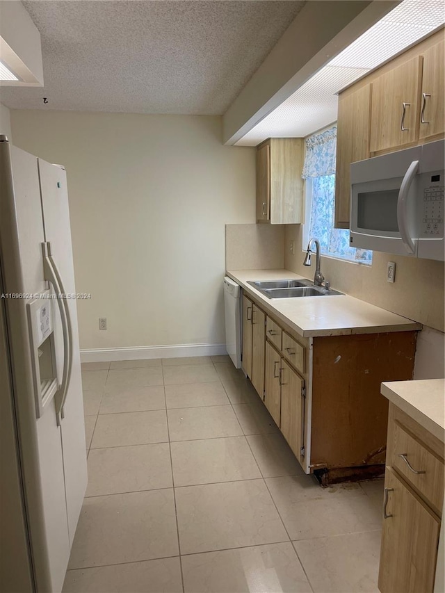 kitchen featuring light tile patterned flooring, a textured ceiling, white appliances, and sink