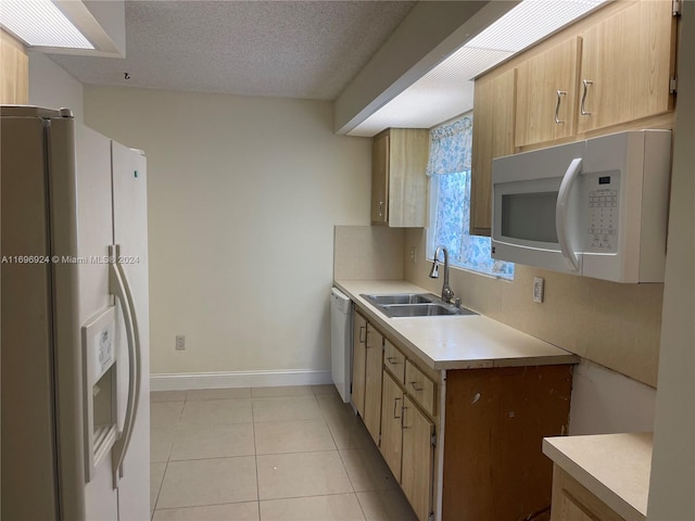 kitchen featuring a textured ceiling, sink, light tile patterned floors, and white appliances