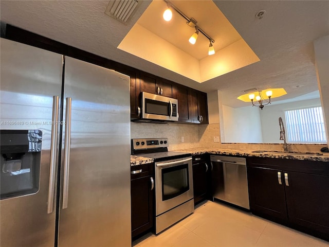 kitchen with decorative backsplash, track lighting, stainless steel appliances, a raised ceiling, and sink