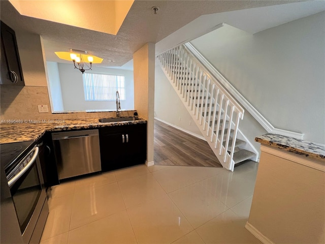 kitchen featuring a textured ceiling, stainless steel appliances, sink, stone counters, and light tile patterned flooring