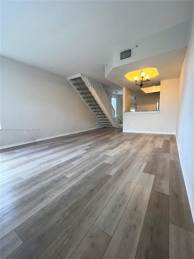 unfurnished living room with hardwood / wood-style flooring and a notable chandelier