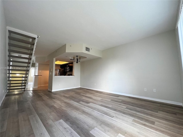 unfurnished living room with wood-type flooring and a notable chandelier