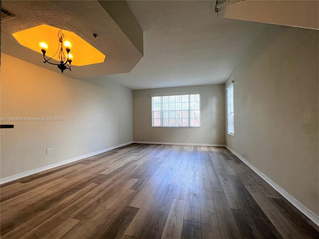 spare room with dark hardwood / wood-style flooring and a chandelier