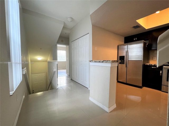 kitchen featuring light stone countertops, stainless steel appliances, and light tile patterned flooring