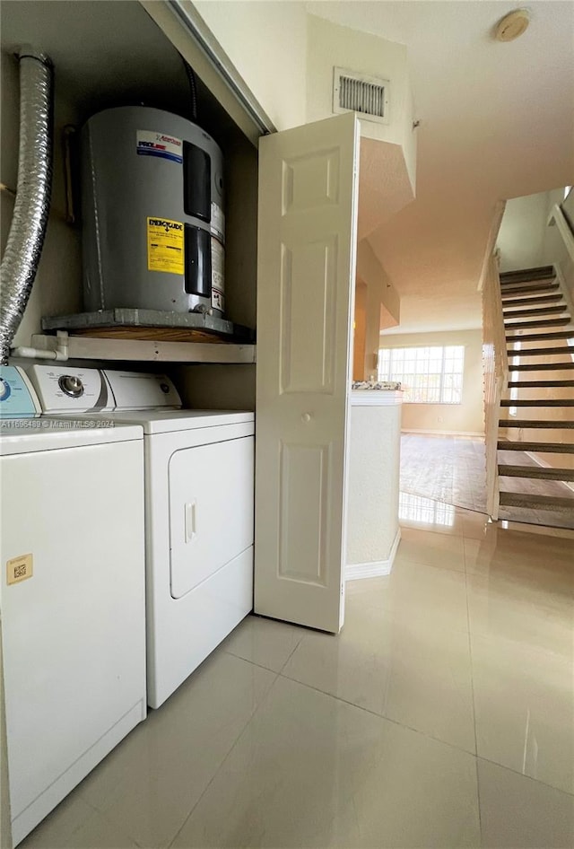 laundry area featuring light tile patterned flooring, electric water heater, and washing machine and clothes dryer