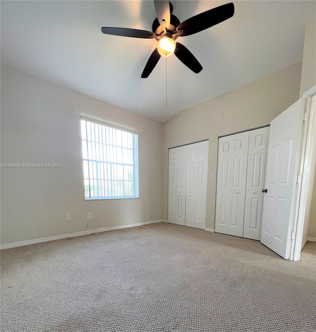 unfurnished bedroom with multiple closets, ceiling fan, and light colored carpet