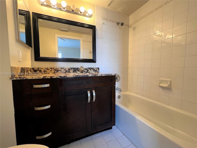 bathroom with tile patterned flooring, vanity, tiled shower / bath combo, and tile walls