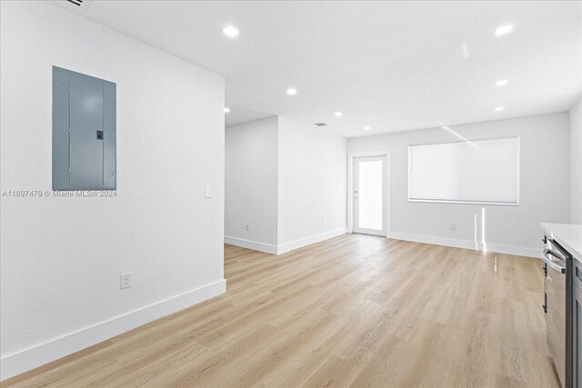 unfurnished living room featuring electric panel and light hardwood / wood-style flooring