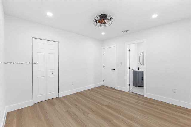 unfurnished bedroom featuring ensuite bath and light hardwood / wood-style floors