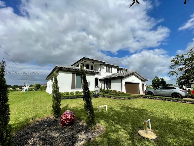 mediterranean / spanish home with a tiled roof, stucco siding, an attached garage, and a front yard