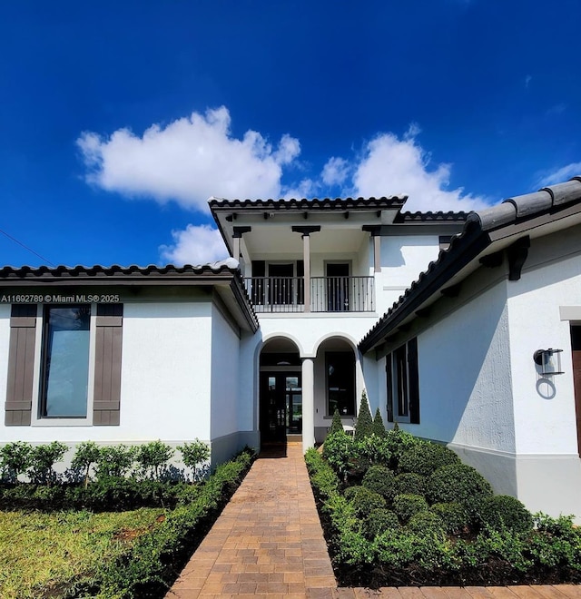 property entrance with french doors, a balcony, and stucco siding