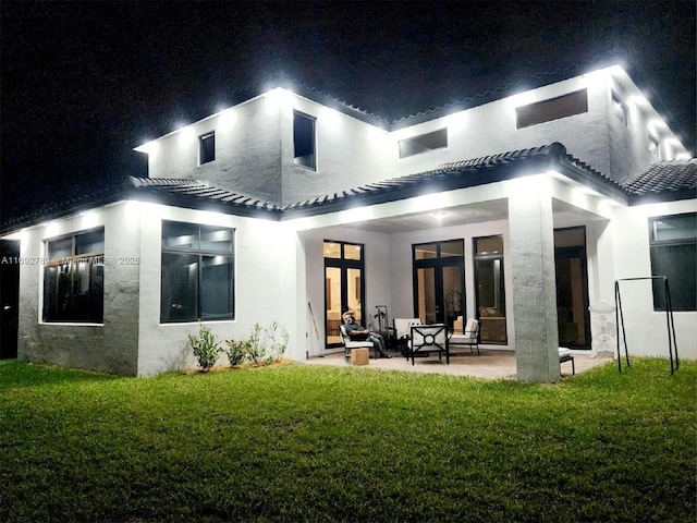 rear view of property with french doors, a patio area, a yard, and stucco siding