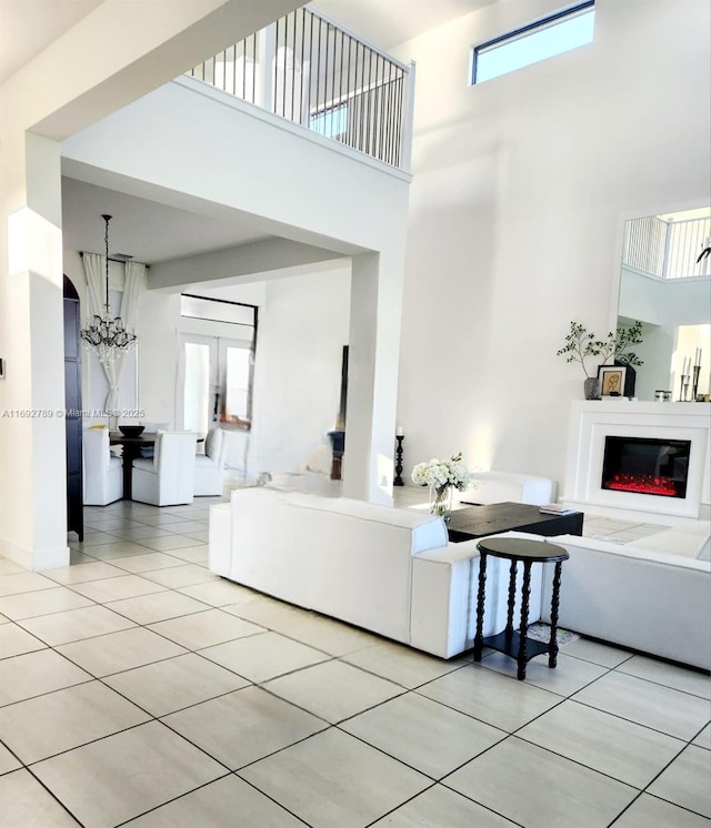 living area featuring light tile patterned floors, a high ceiling, a chandelier, and a wealth of natural light