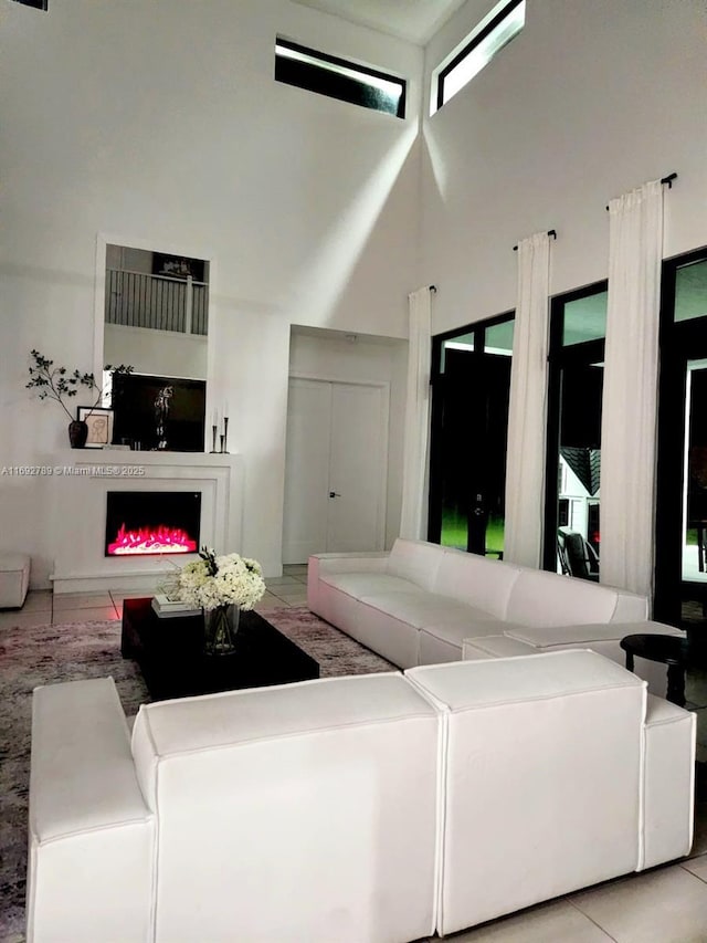 living area featuring tile patterned flooring, a fireplace, and a high ceiling