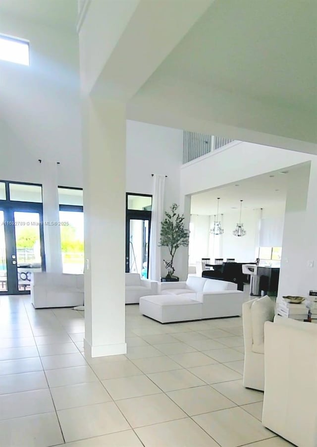 living area with a wealth of natural light, a high ceiling, and light tile patterned floors