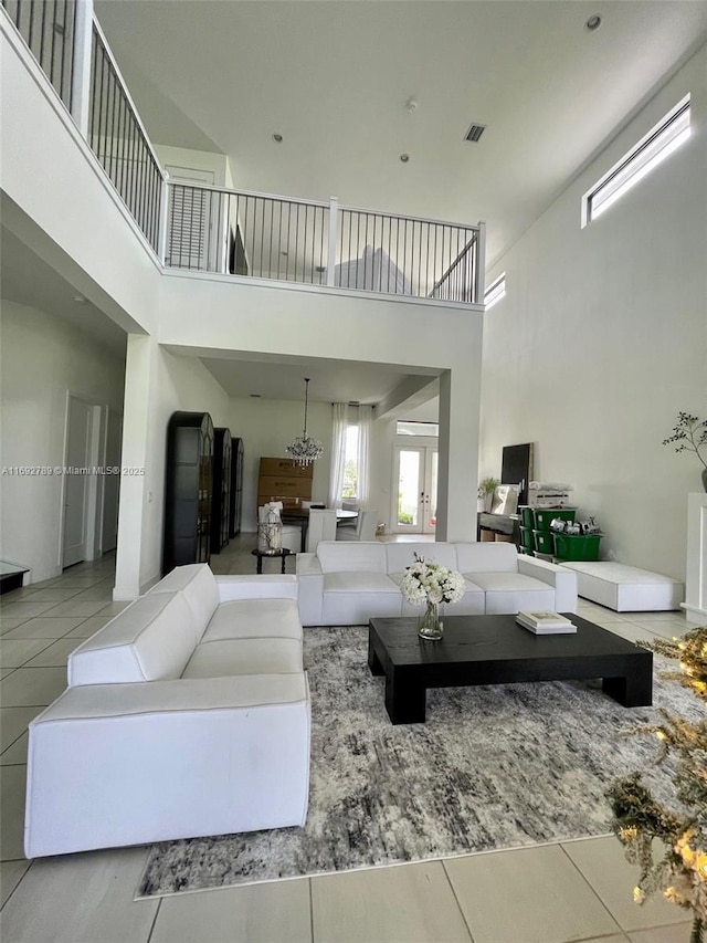 tiled living room featuring a chandelier and a high ceiling