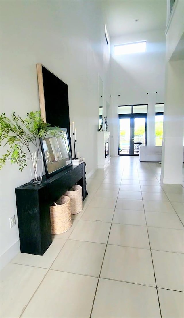 hall featuring baseboards, a high ceiling, and light tile patterned floors