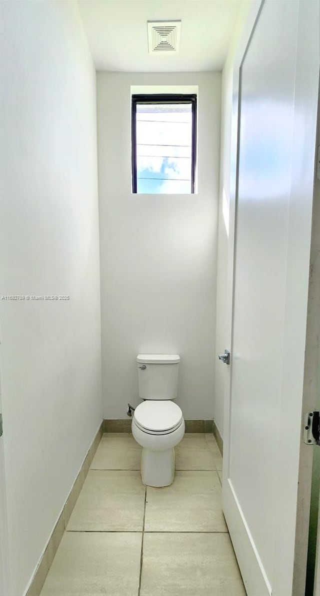 bathroom featuring toilet, tile patterned flooring, visible vents, and baseboards