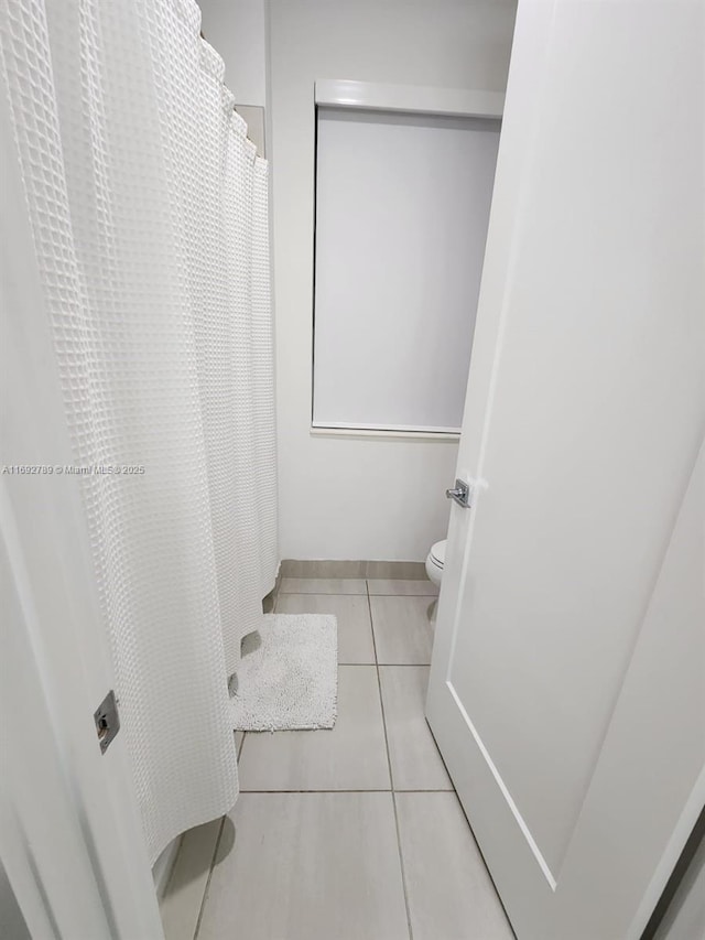 full bath featuring tile patterned flooring, toilet, and baseboards