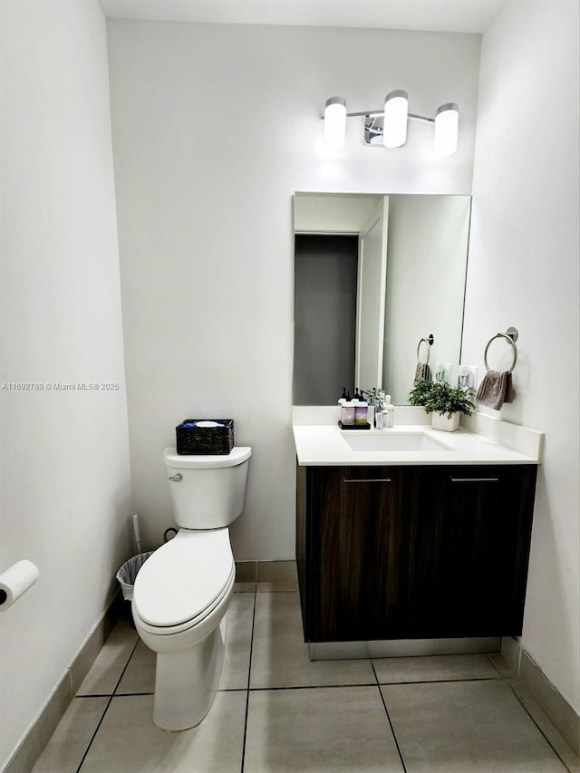 half bathroom featuring tile patterned flooring, vanity, toilet, and baseboards