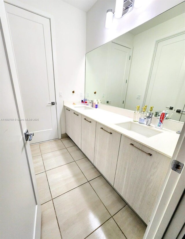 full bath featuring double vanity, a sink, and tile patterned floors