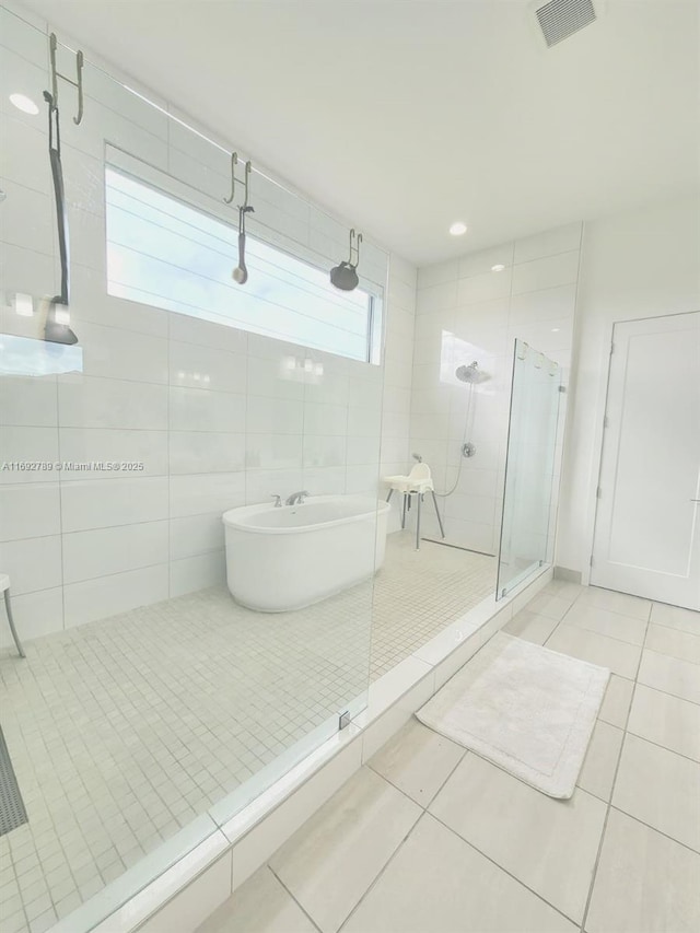 full bathroom featuring a freestanding bath, a shower stall, visible vents, and tile patterned floors