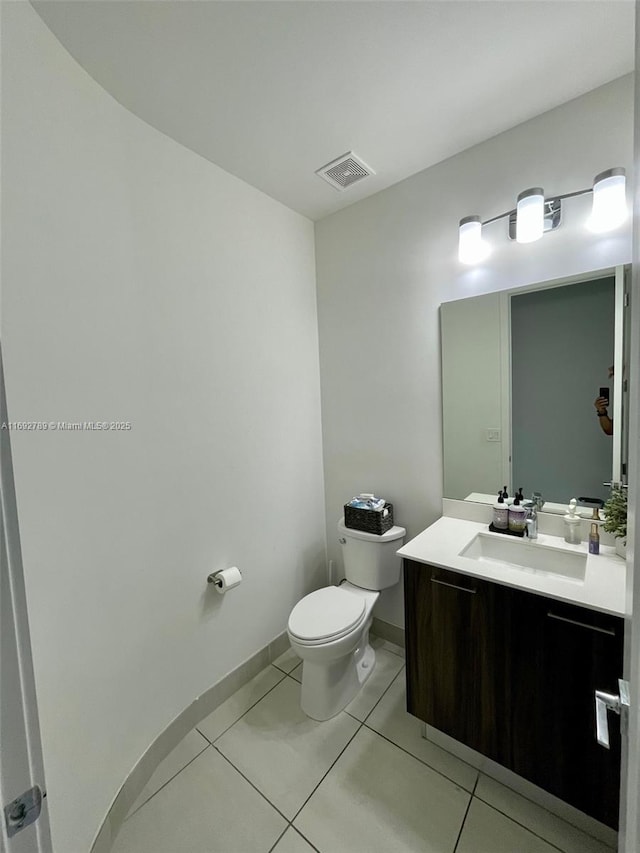 half bath with baseboards, visible vents, toilet, tile patterned floors, and vanity