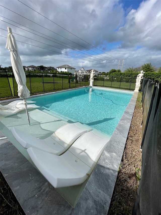 view of swimming pool featuring a fenced in pool, a water slide, a fenced backyard, and a lawn