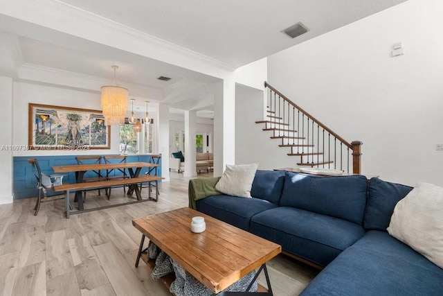 living room with ornamental molding, light hardwood / wood-style floors, and a notable chandelier