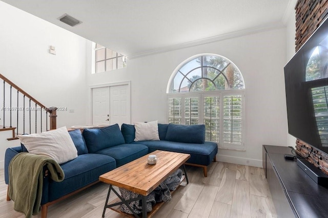 living room with a high ceiling, light hardwood / wood-style floors, and crown molding