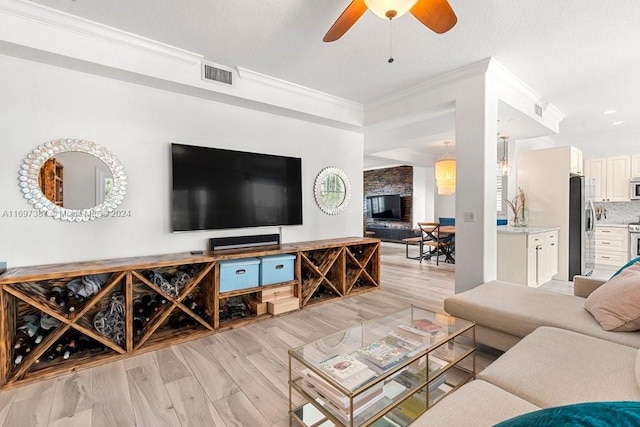 living room featuring ceiling fan, light wood-type flooring, and ornamental molding