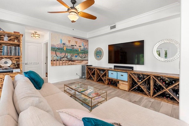 living room with ceiling fan, ornamental molding, and light wood-type flooring