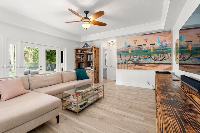 living room with french doors, a raised ceiling, crown molding, ceiling fan, and light hardwood / wood-style floors