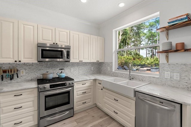 kitchen with decorative backsplash, light stone countertops, ornamental molding, and appliances with stainless steel finishes