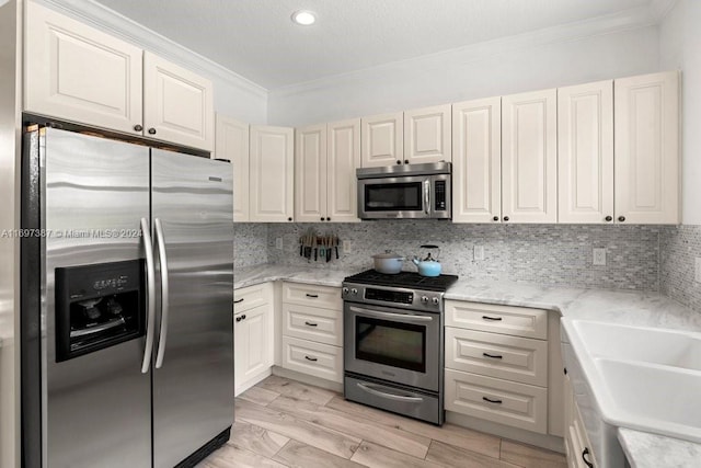 kitchen with backsplash, crown molding, light hardwood / wood-style flooring, and stainless steel appliances