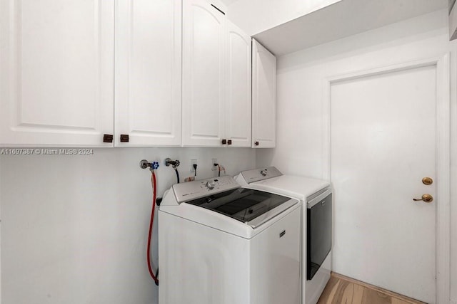 laundry room featuring cabinets, light hardwood / wood-style flooring, and washer and clothes dryer