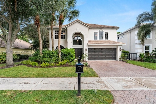 mediterranean / spanish home with a garage and a front lawn