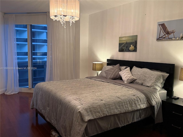 bedroom with dark hardwood / wood-style floors and an inviting chandelier