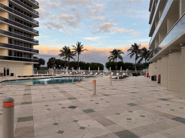 pool at dusk featuring a patio area