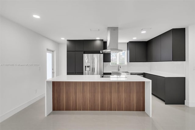 kitchen featuring stainless steel refrigerator with ice dispenser, light tile patterned floors, a kitchen island, and wall chimney exhaust hood