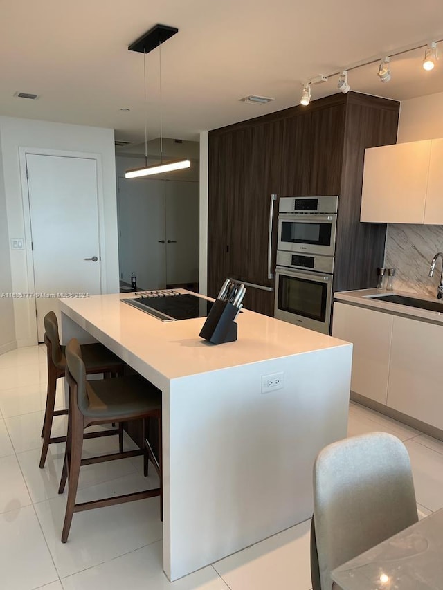 kitchen with dark brown cabinets, sink, pendant lighting, a center island, and white cabinetry