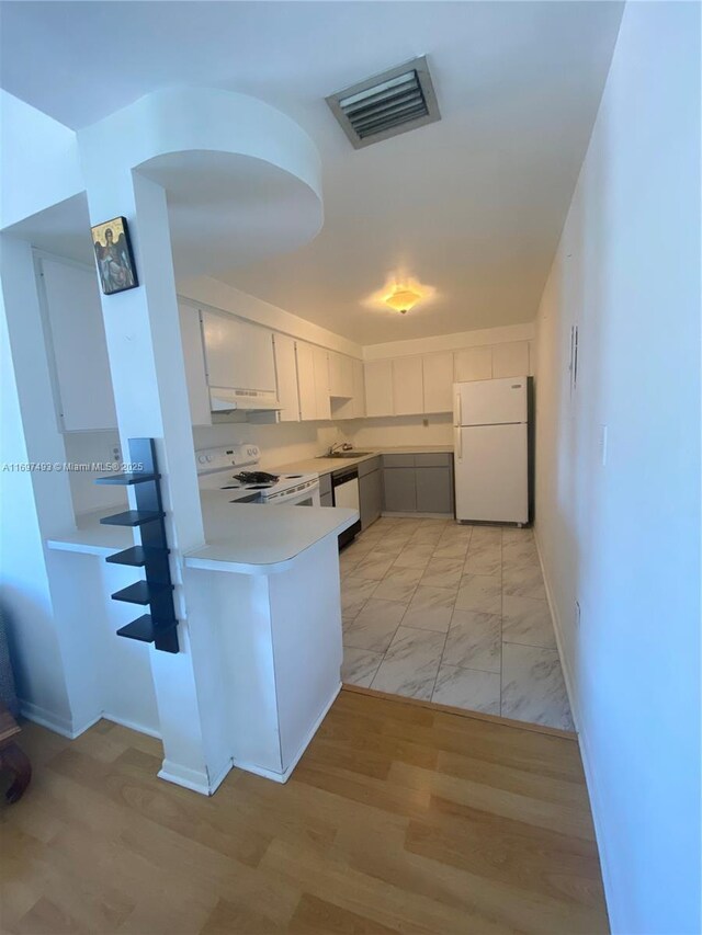 kitchen with white appliances, light hardwood / wood-style flooring, and white cabinetry