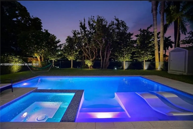 pool at dusk featuring an in ground hot tub