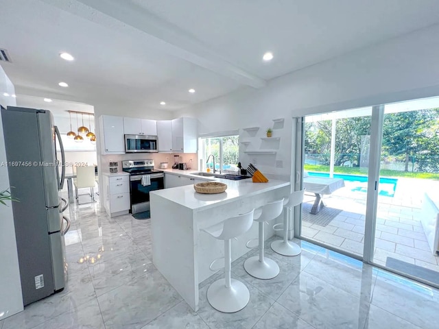 kitchen with beam ceiling, white cabinetry, kitchen peninsula, a kitchen bar, and appliances with stainless steel finishes