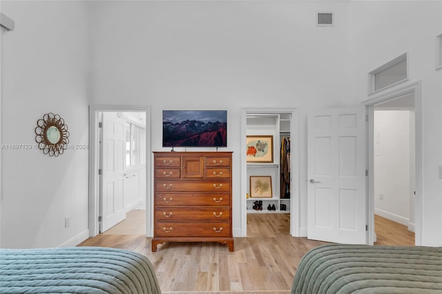 bedroom with light hardwood / wood-style floors and a high ceiling