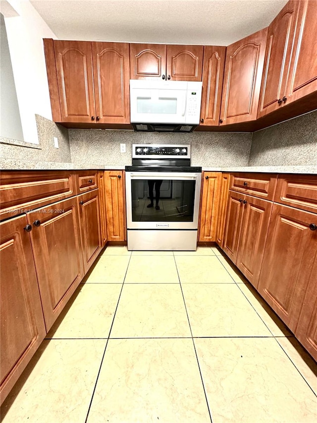 kitchen with stainless steel electric range, light tile patterned flooring, and tasteful backsplash