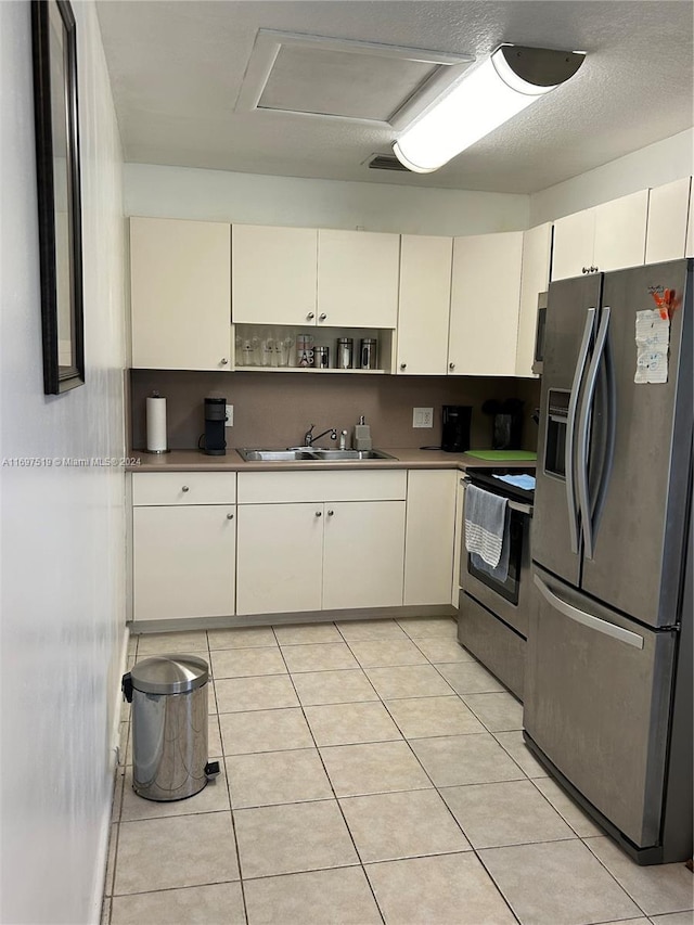 kitchen featuring white cabinets, sink, light tile patterned floors, a textured ceiling, and appliances with stainless steel finishes