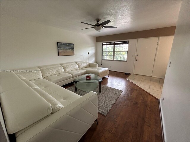 living room featuring ceiling fan, dark hardwood / wood-style flooring, and a textured ceiling