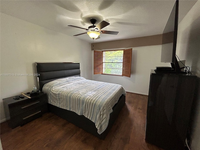 bedroom with a textured ceiling, ceiling fan, and dark hardwood / wood-style floors