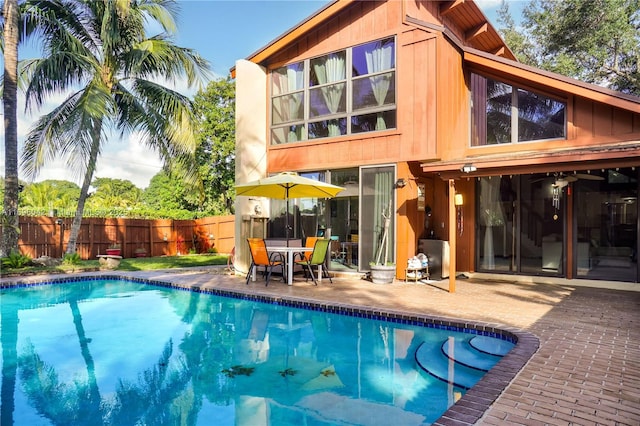 rear view of property featuring a fenced in pool and a patio area